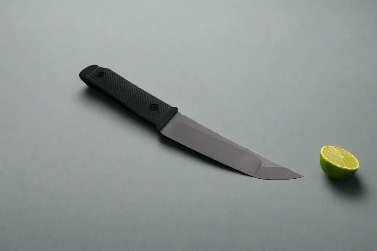 Fixed blade Kwaiback Knife, black G10 handle, stone wash blade, on a dark surface