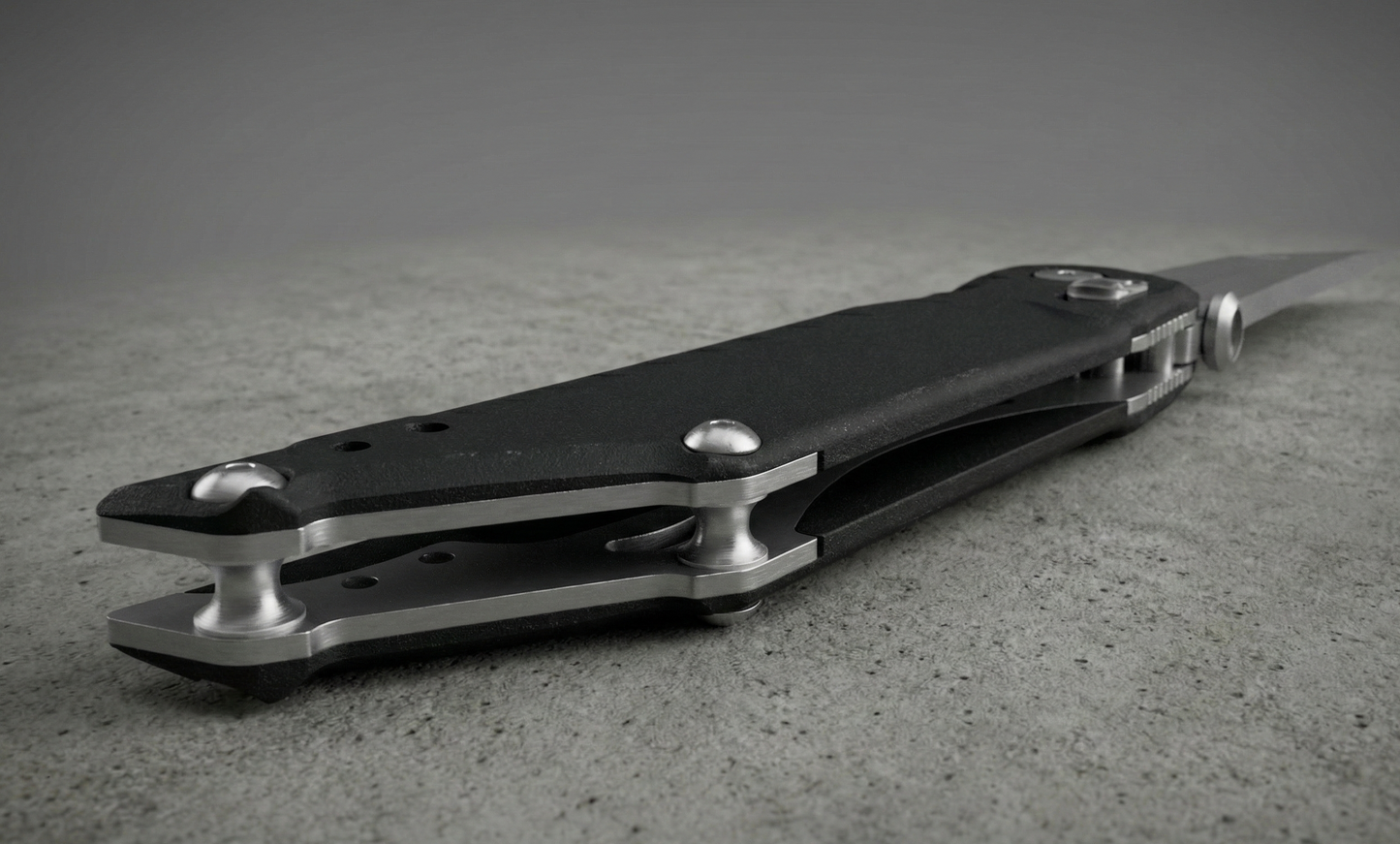 Black and silver pocket knife on a textured surface with a neutral background
