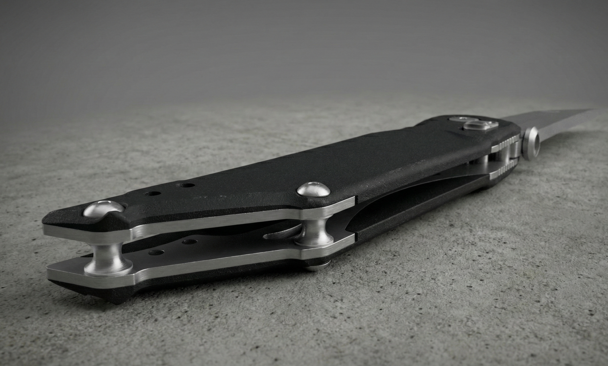 Black and silver pocket knife on a textured surface with a neutral background