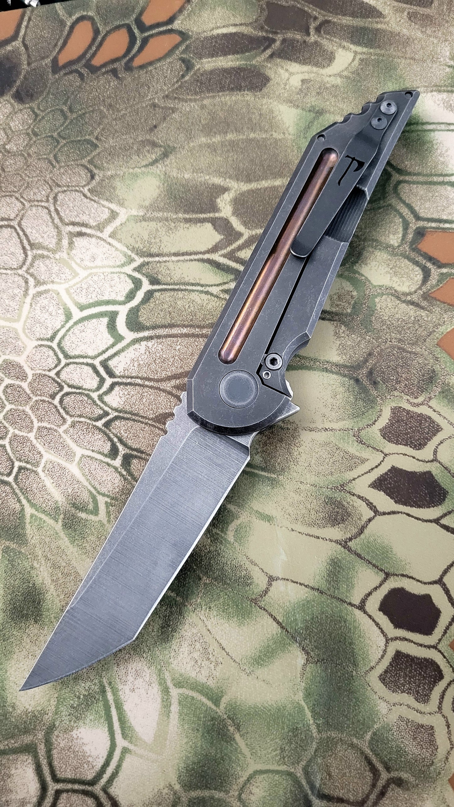 Folding knife on a camouflage-patterned surface